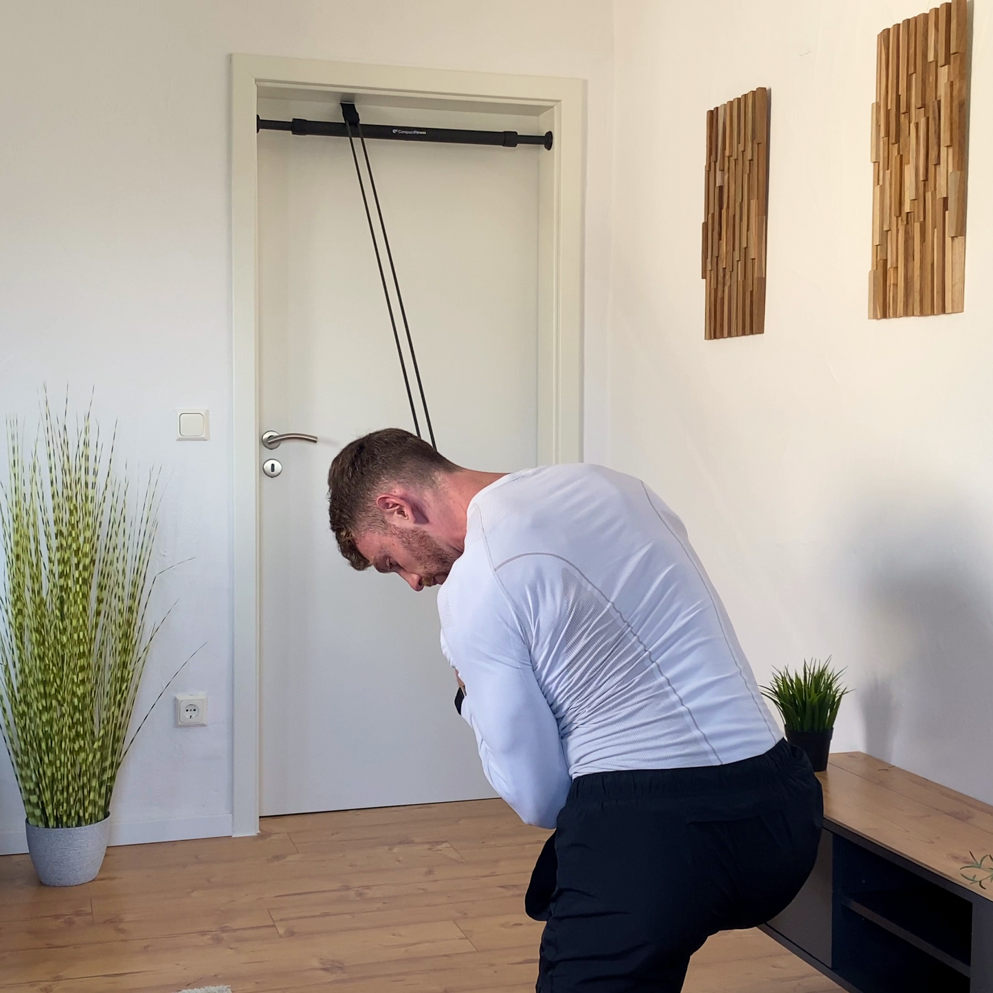 Exercice de tirage avec élastique de résistance utilisant l'ancrage de porte comme une poulie haute.